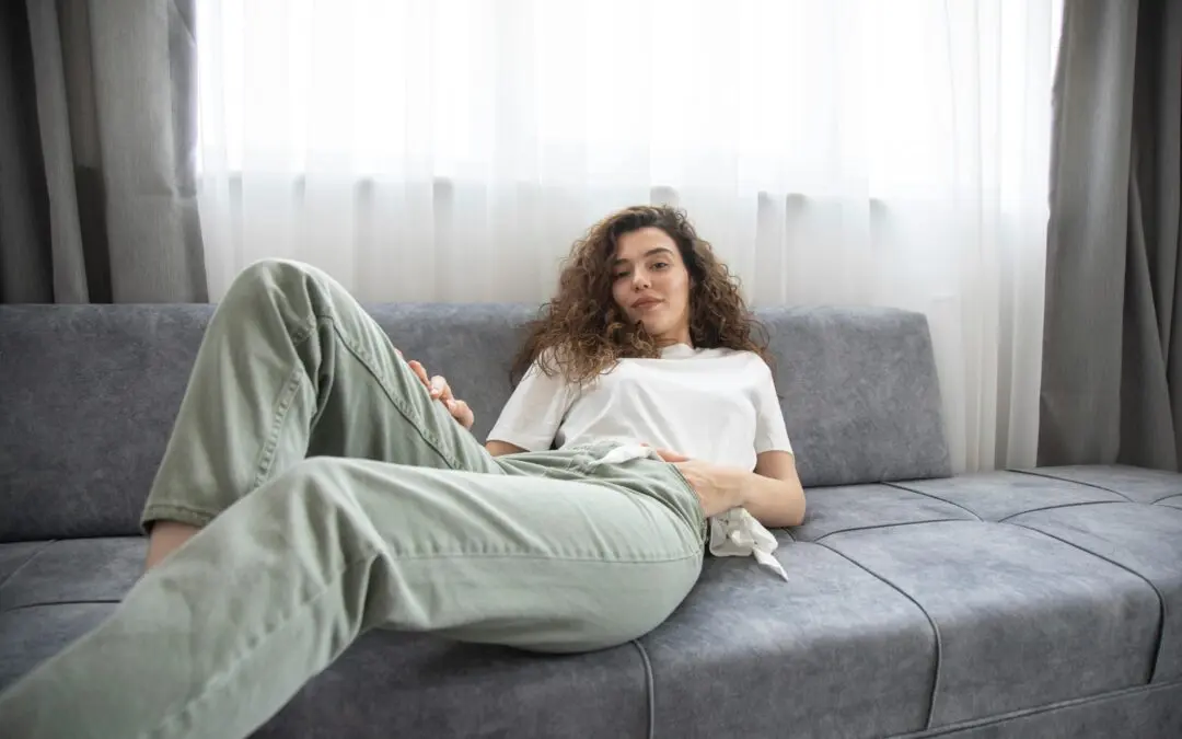 Femme détente sur canapé gris, intérieur lumineux