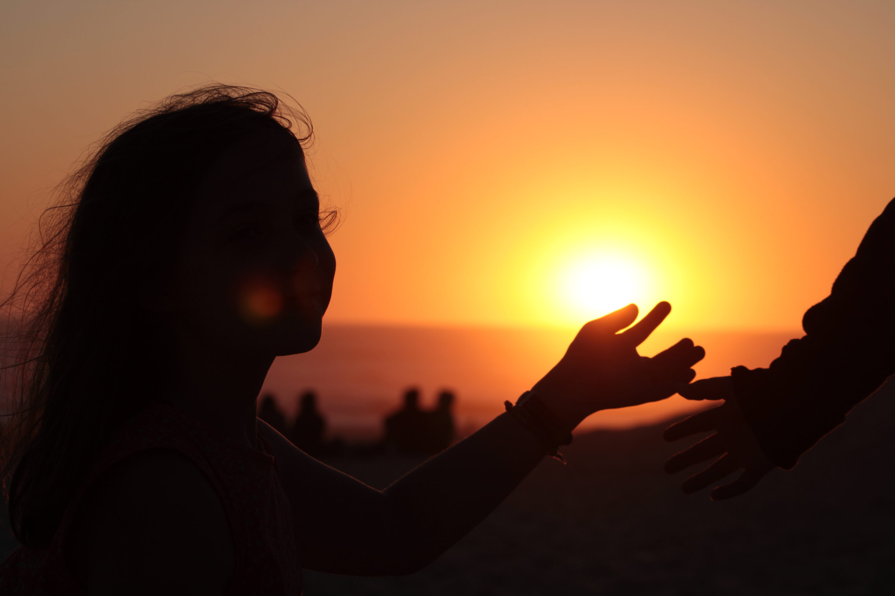 Fille touchant main adulte au coucher du soleil